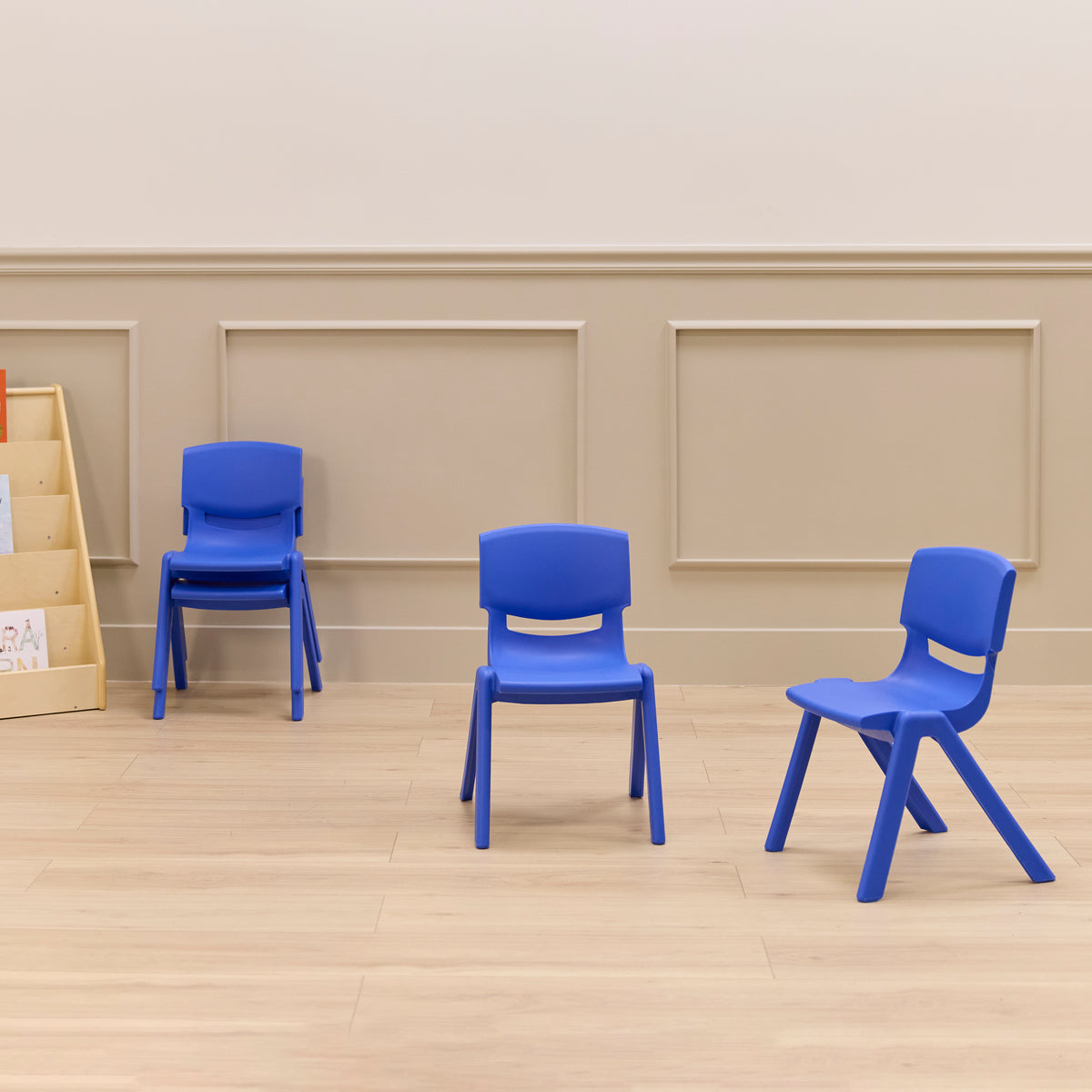 Four blue plastic chairs with curved backs and angled legs arranged on a wooden floor.