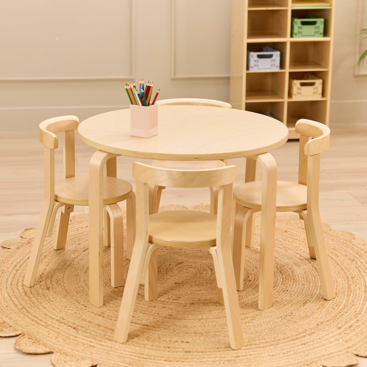 Natural bentwood round table with four curved chairs and pencil holder on jute rug.