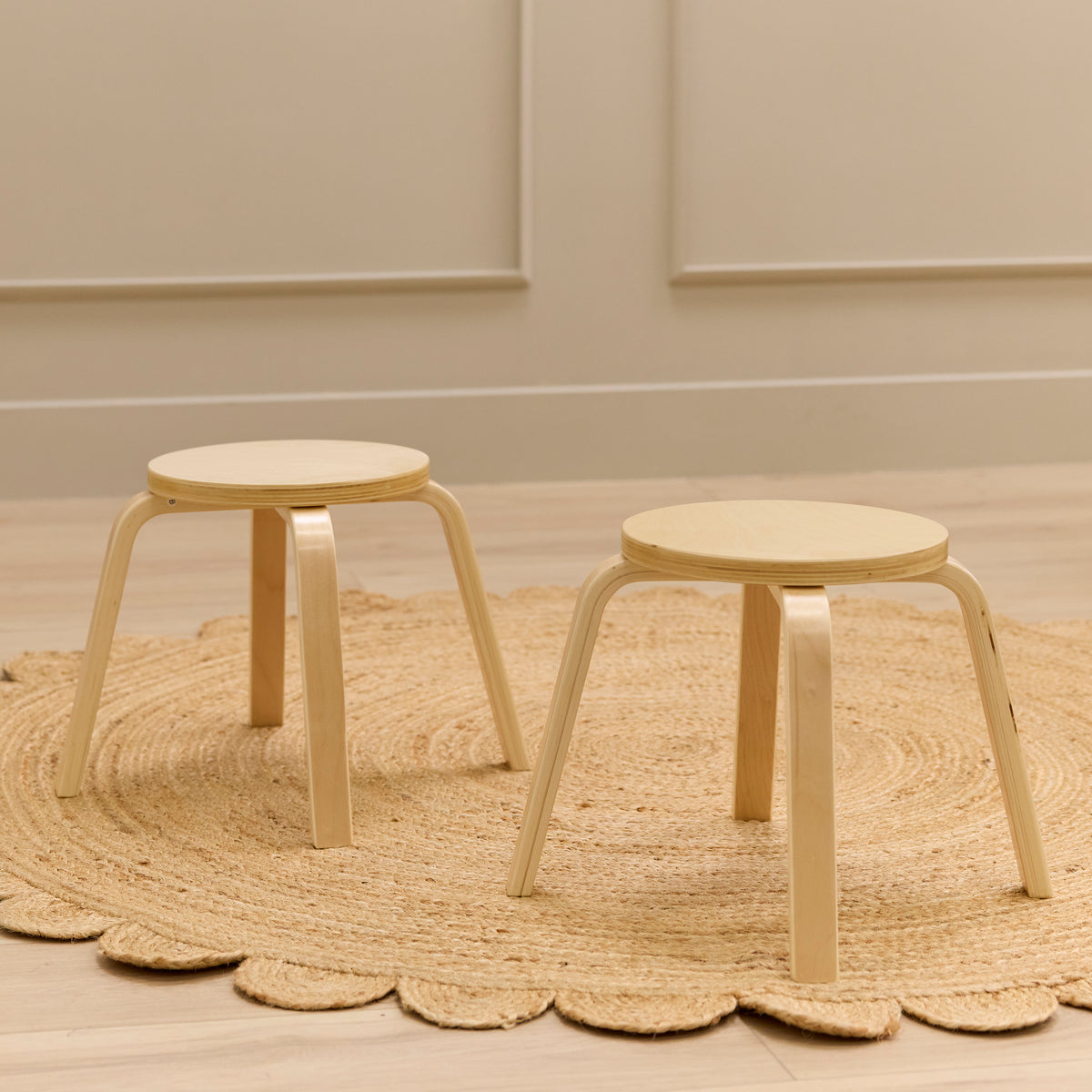 Two bentwood stools with round cream seats and natural wood legs on a jute rug.
