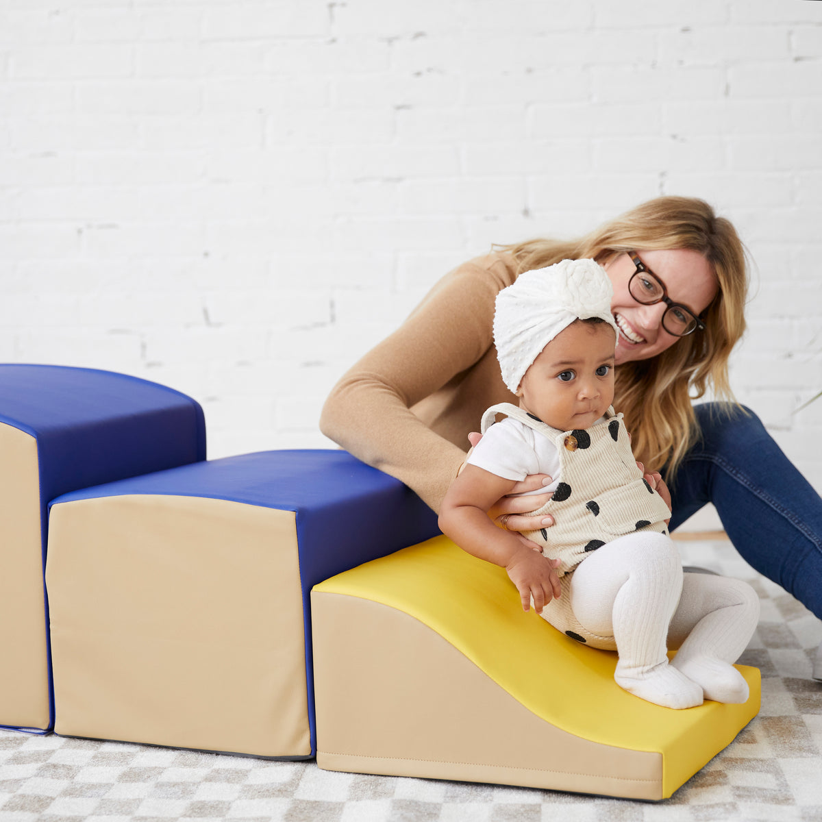 Adult and toddler on yellow climbing ramp attached to cardboard block base.