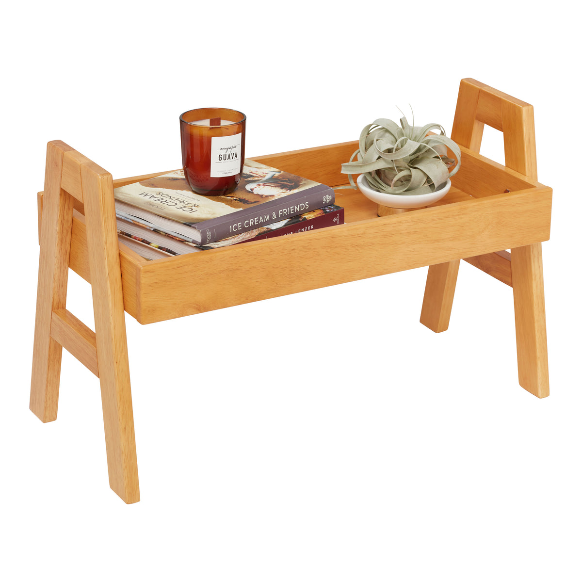 Natural wood stacking shelf organizer with handles holding books, candle, and decorative items.