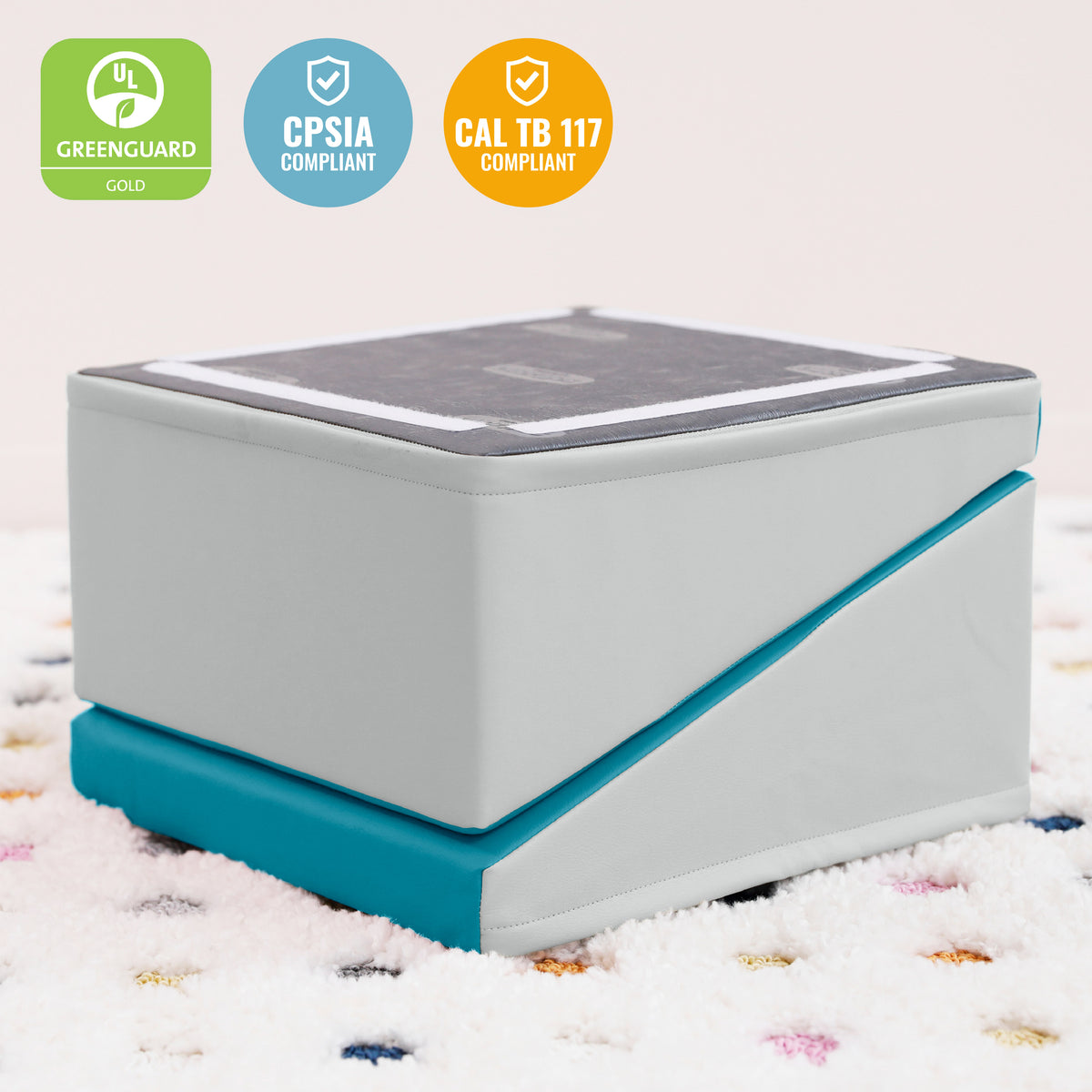 White and teal padded step stool with dark gray top surface on patterned carpet.