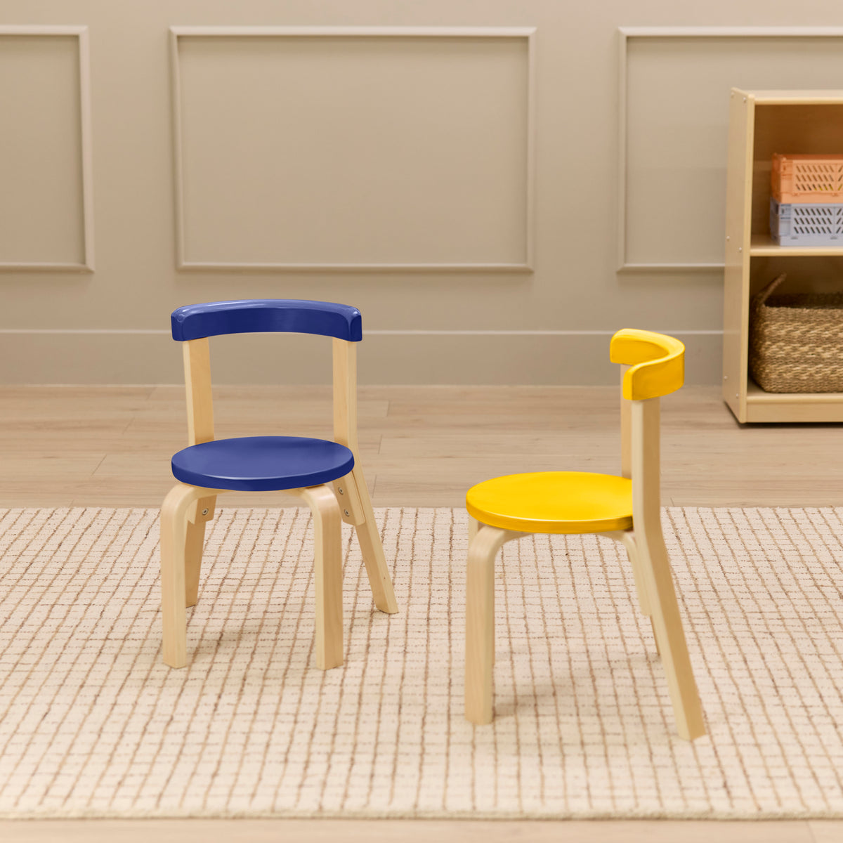 Natural wood chairs with blue and yellow curved seats and backs on a beige rug.